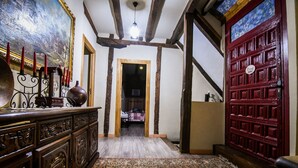 Un corridoio con pavimento in legno, tappeto decorato, una porta rossa e un quadro appeso al muro.