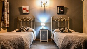 Una stanza con due letti, un comodino con una lampada e opere d'arte alle pareti.