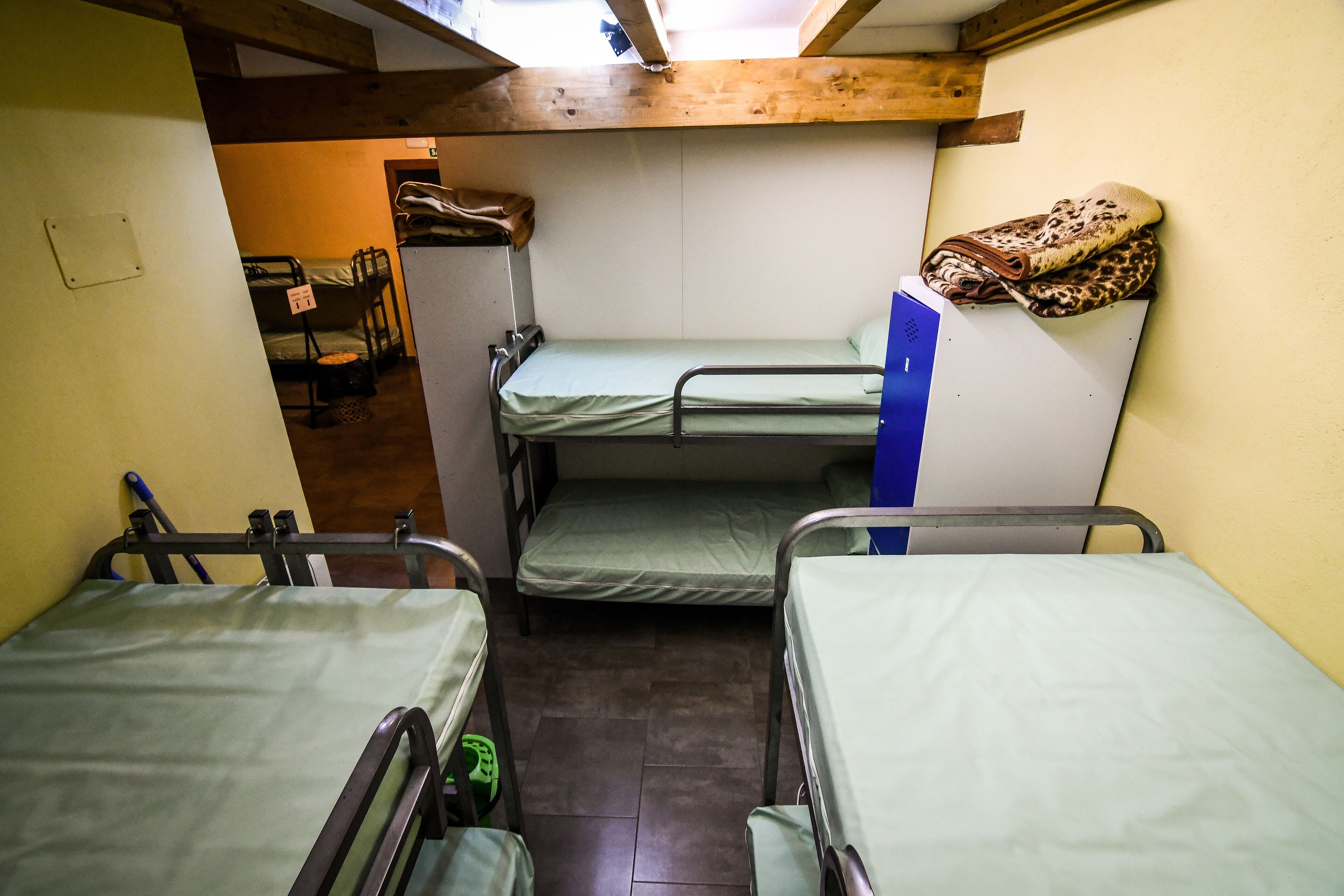 Un dormitorio con literas, una mesita pequeña y una banca.