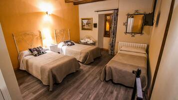A room with two beds, wooden flooring, a painting on the wall, and a mirror.