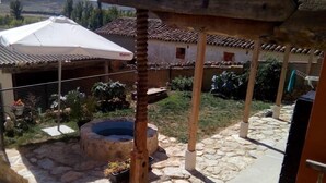 Un'area patio esterna con pavimento in pietra, una struttura a pergola e un elemento d'acqua.