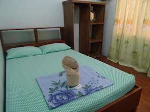 A single bed with a green polka dot bedspread and a floral pillow. A wooden nightstand is beside the bed. - Tay LeLong's Pension House (Taytay)