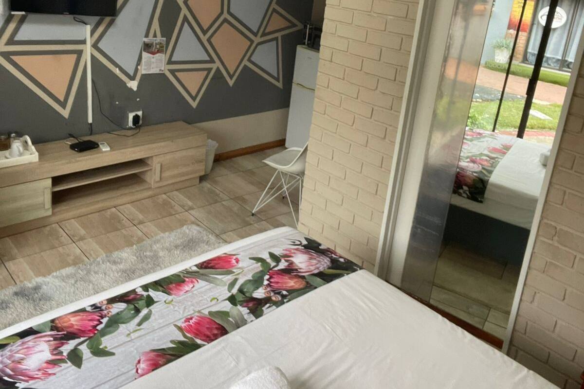 Une chambre d’hôtel avec un lit, un téléviseur fixé au mur, un miroir et un mur en briques.