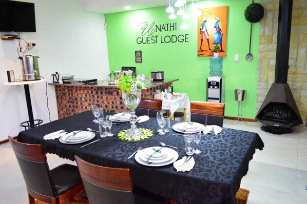 Un comedor con pared verde, mostrador de ladrillo y chimenea.