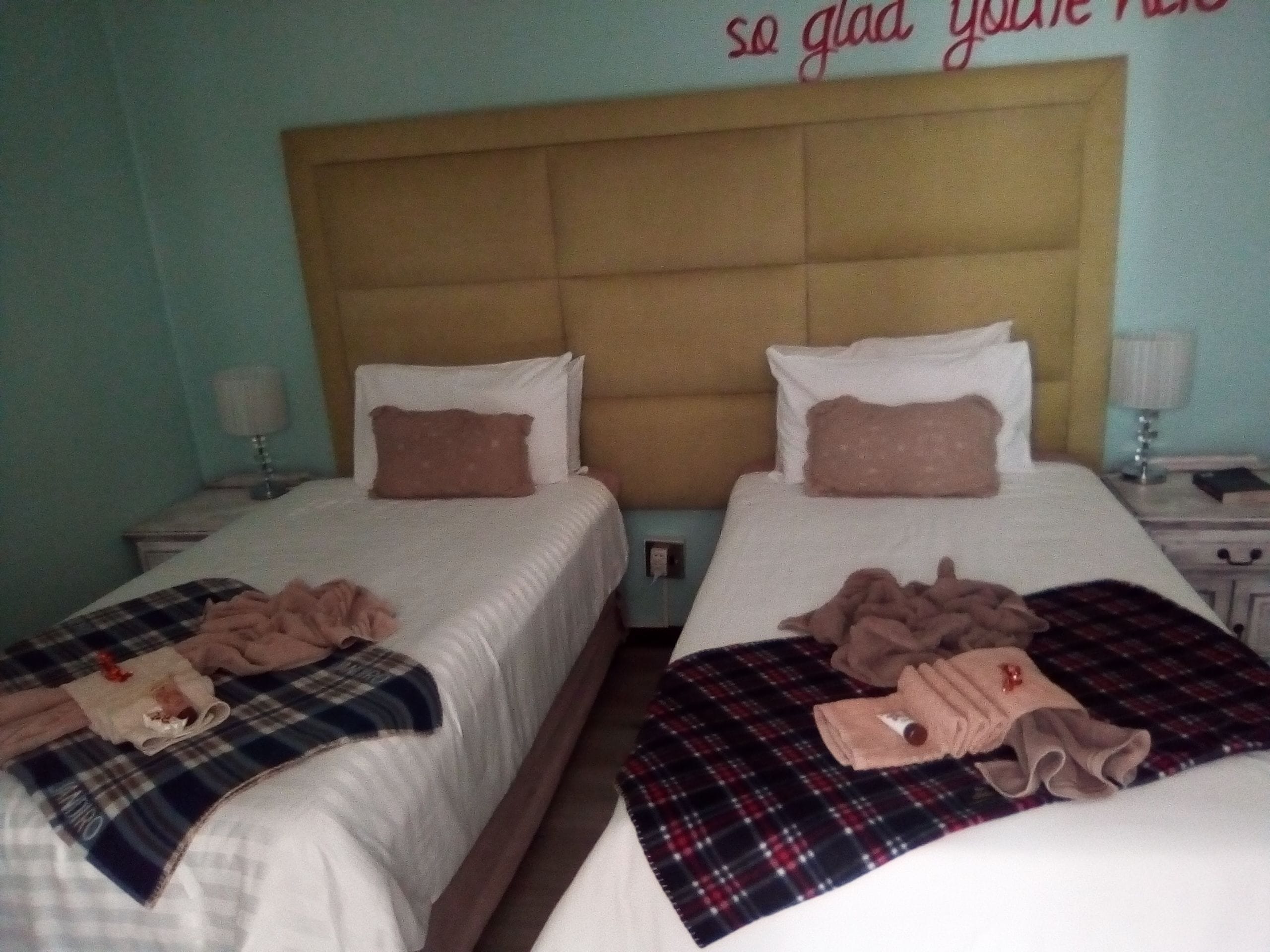 Two twin beds with headboards, a bedside table with a lamp, and a wall with a partial text.