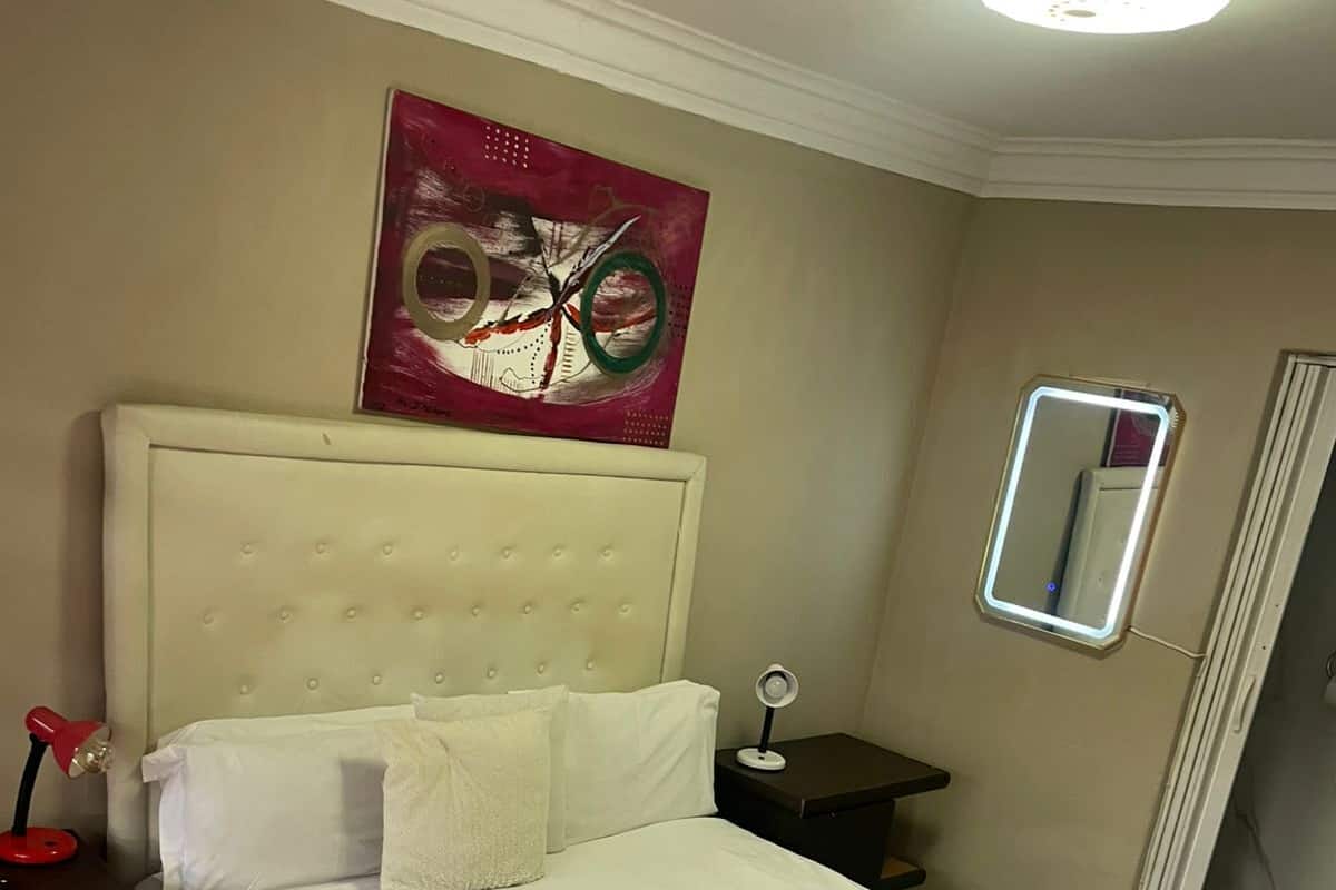 Un lit bien fait, avec des draps blancs, un plaid rouge et une tête de lit.