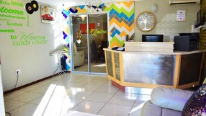 Un espace d’accueil doté d’une porte-fenêtre, d’un comptoir de réception et d’un mur orné d’un motif en chevrons.