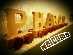 Wooden letters spelling "PARAS" with a "welcome" sign below, set against a textured wall. - Pharos zur Seeve (Seevetal)