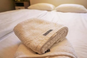 A neatly made bed with a folded white towel on top. - Pharos zur Seeve (Seevetal)