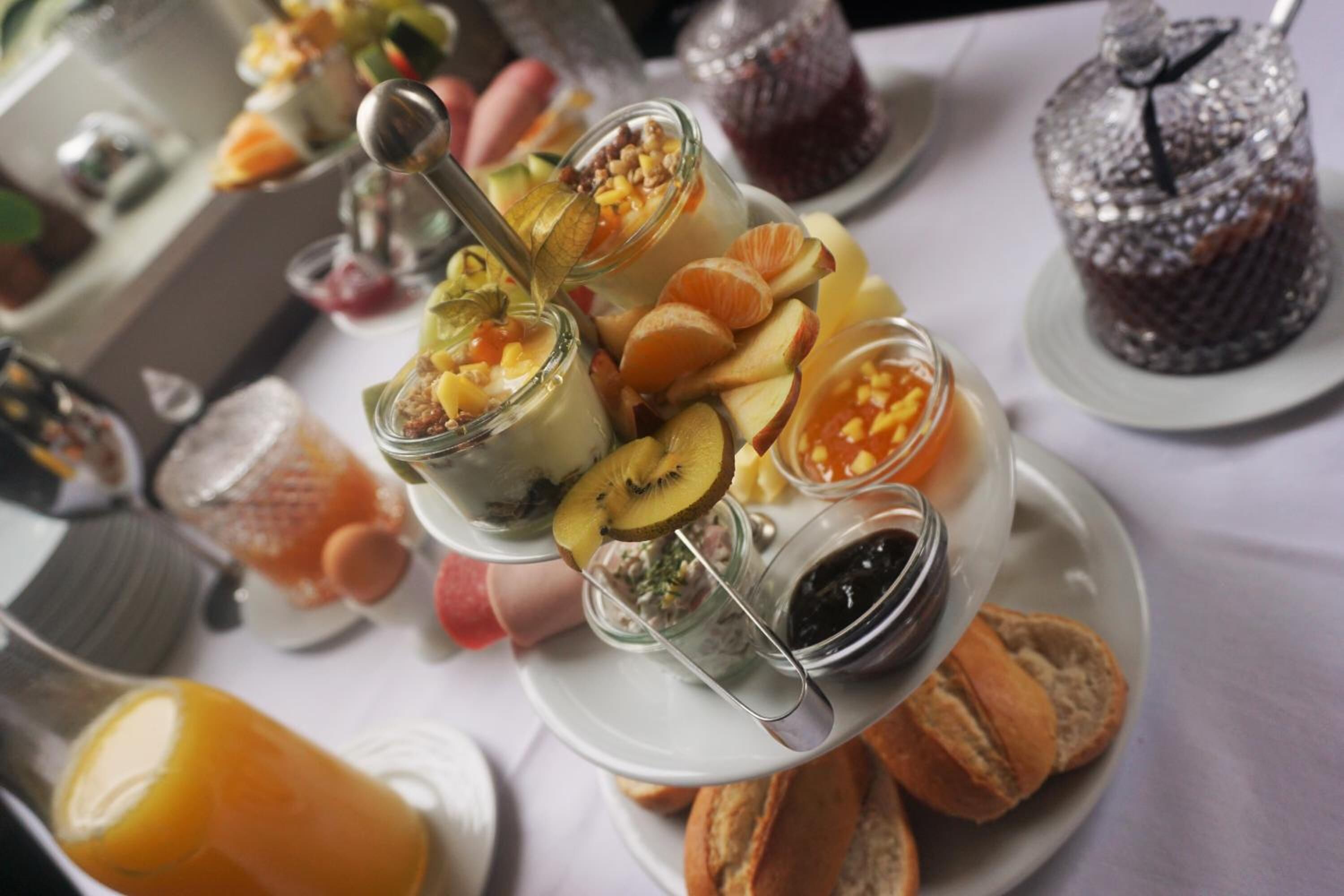 A dessert buffet with various fruit, nuts, and a cake on a white tablecloth.