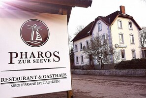 A sign for 'PHAROS ZUR SEEVE' restaurant and gasthaus with a view of a historic building in the background. - Pharos zur Seeve (Seevetal)