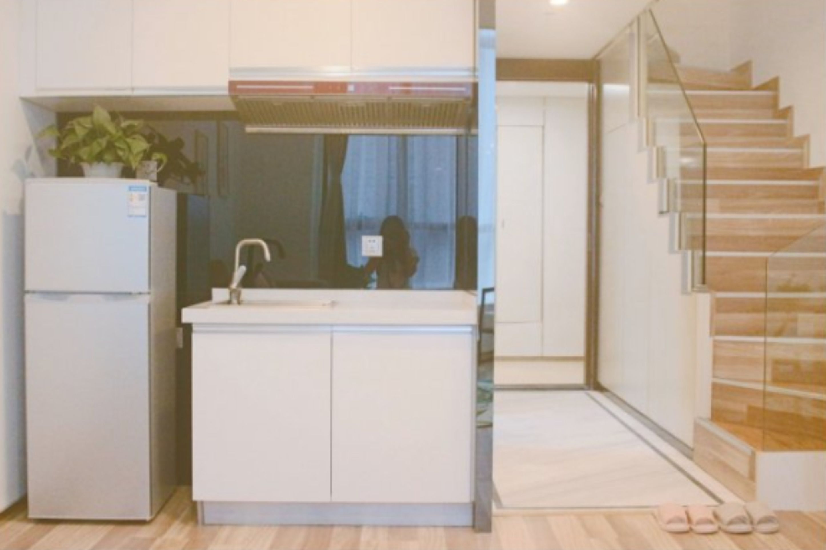 Una cocina moderna con refrigerador empotrado, un lavamanos y una puerta de vidrio que da a una escalera.