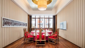 Un comedor con una mesa redonda dispuesta para seis personas, rodeada de sillas de madera con cojines rojos.