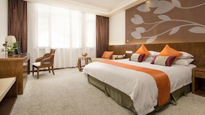 Una habitación de hotel con una cama grande, un escritorio, una silla y una mesita de noche con una lámpara.