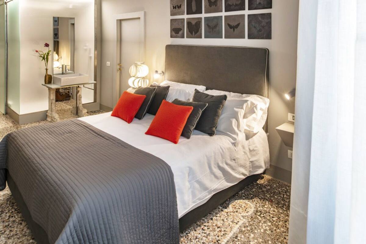 Un dormitorio moderno con una cama grande, una mesita de noche, un espejo y decoración en la pared.