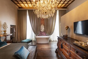 A spacious bedroom with a large bed, a wooden dresser, a vanity, and a bathtub. - Casa Botticelli (Florence)