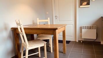 A dining area with a wooden table and chairs, a white door, and a wall-mounted air conditioning unit.