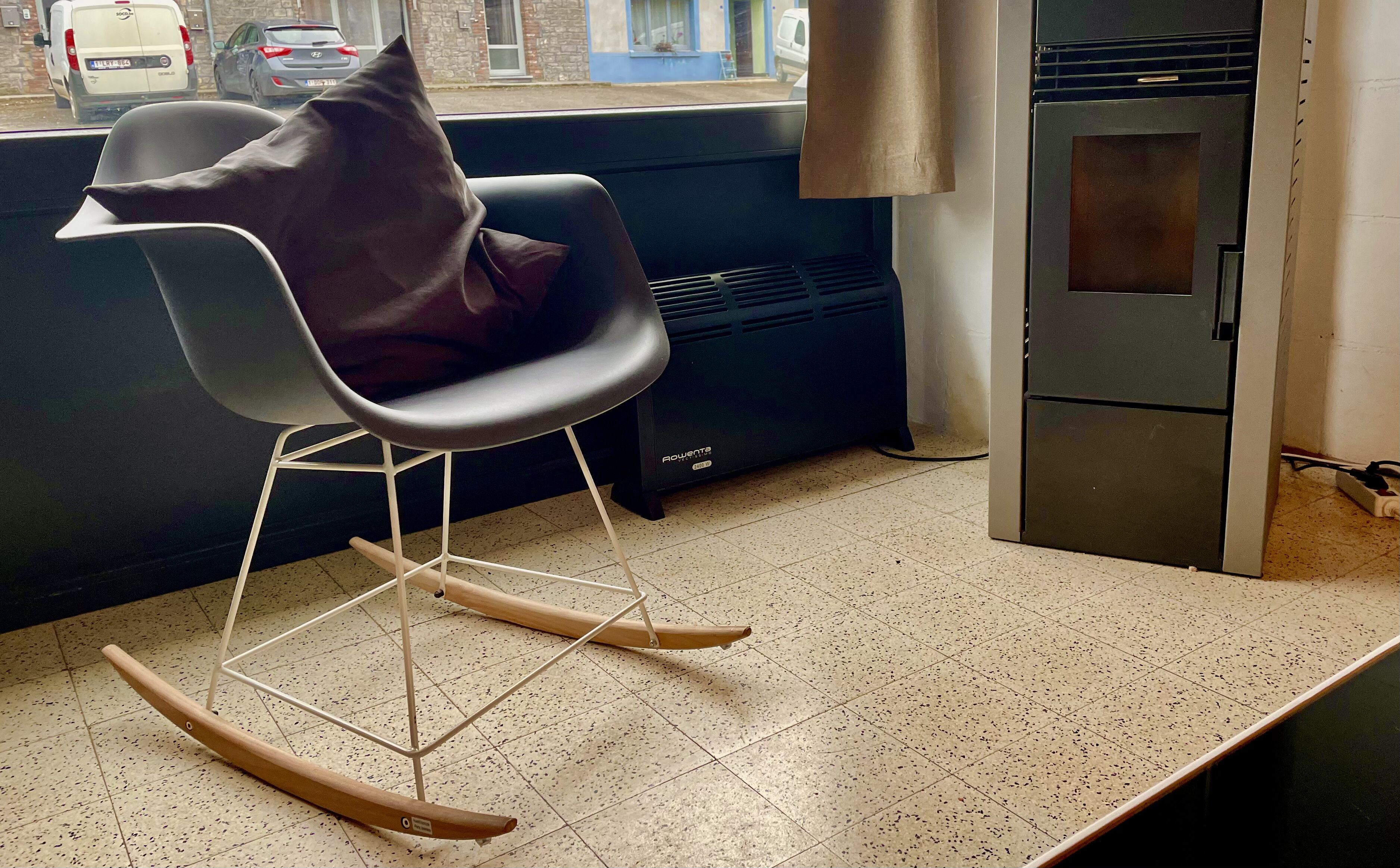 Une cuisine moderne avec un fauteuil à bascule, un four encastré et une fenêtre donnant sur les voitures garées à l’extérieur.
