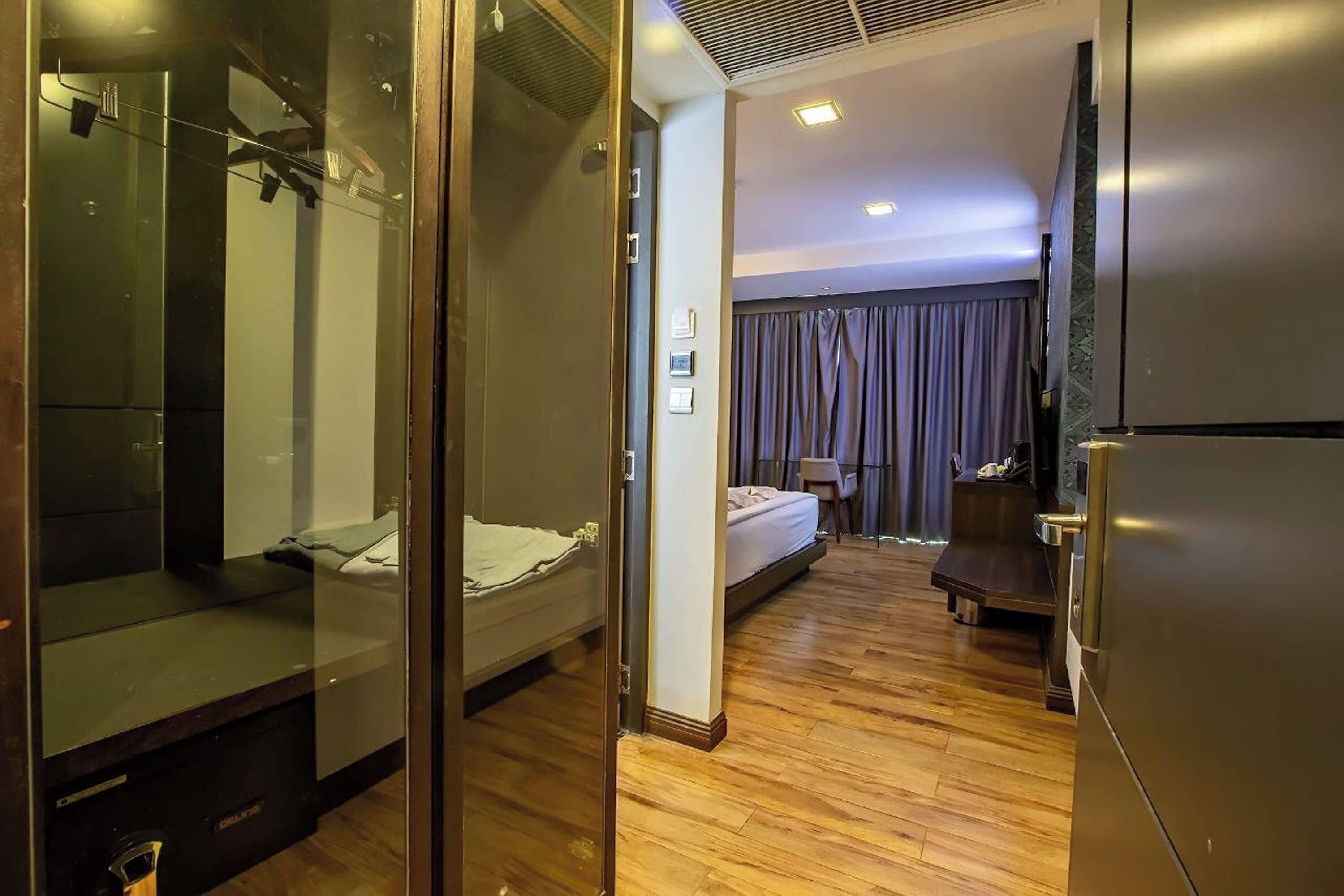 A hotel room with a bed, a desk, a mirror, and a wardrobe.