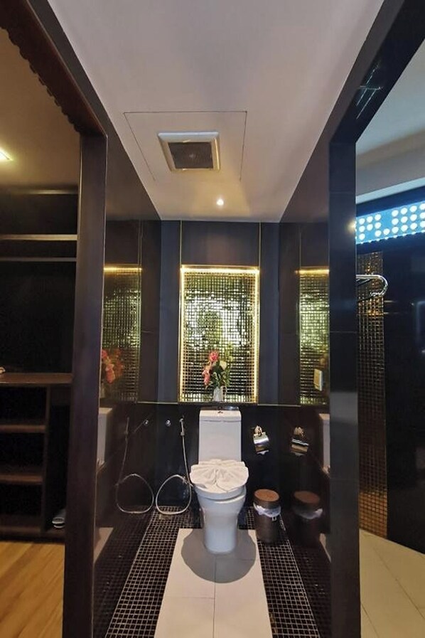 Un baño moderno con inodoro blanco, cabina de ducha con mampara de vidrio y un revestimiento decorativo con un diseño luminoso.