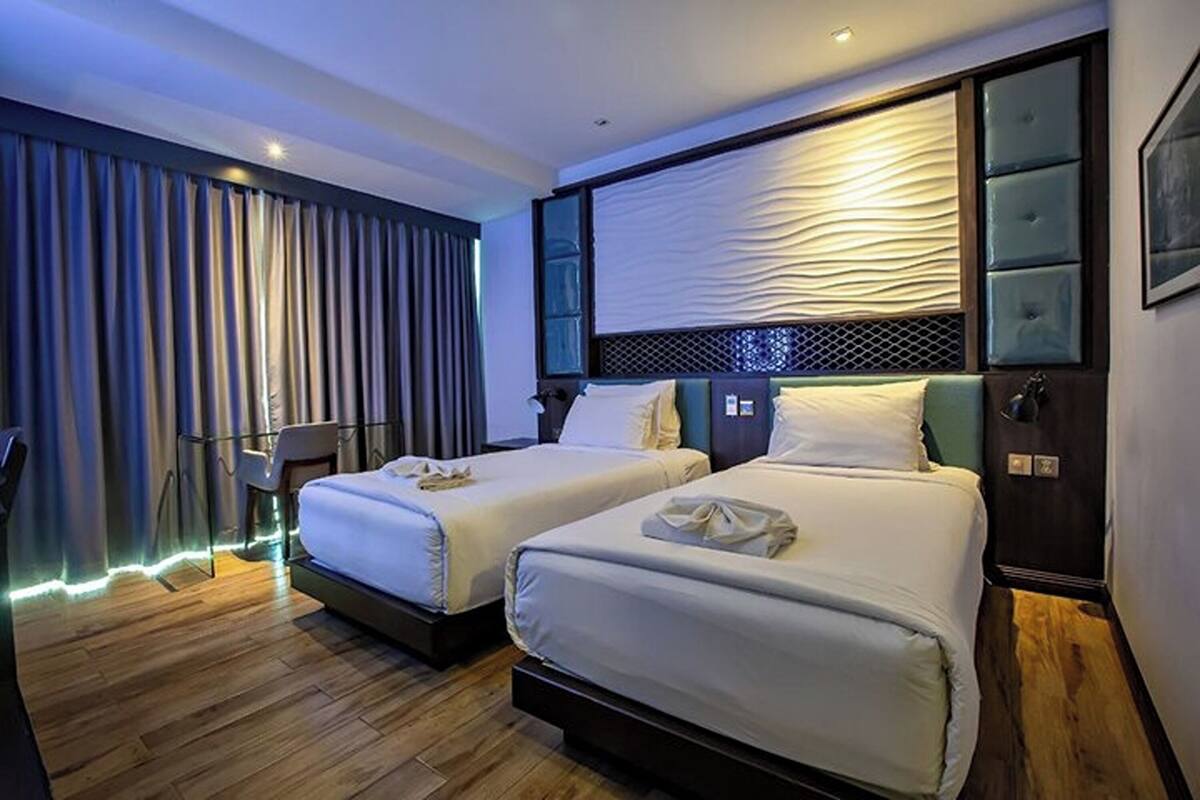 A hotel room with two beds, a desk, and a chair.