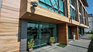Un edificio moderno con amplios ventanales de vidrio, fachada de madera y plantas en macetas al frente.