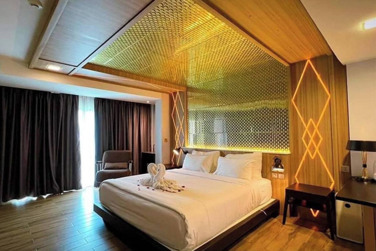 A hotel room with a large bed, a desk, and a chair.