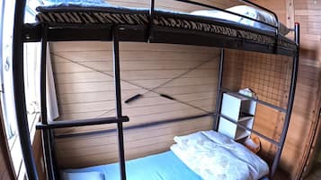 A bunk bed with a wooden headboard and a small shelf unit beside it.