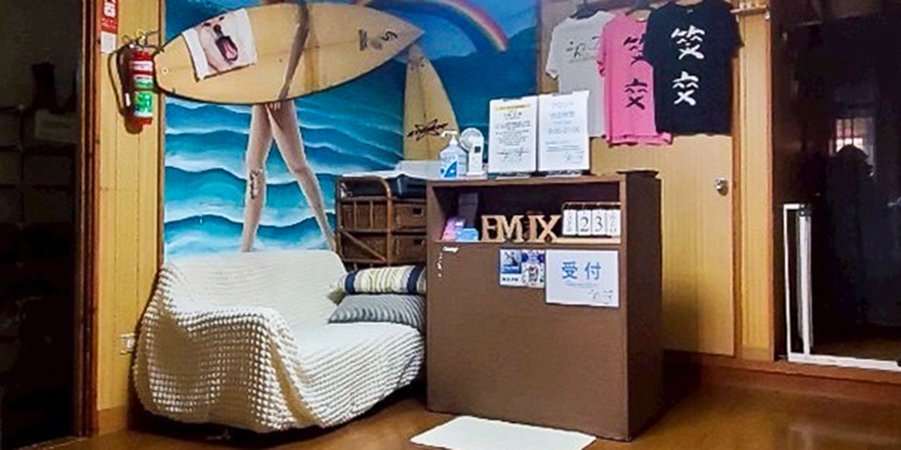 A room with a beach-themed mural, a wicker chair, a reception desk, and a surfboard.