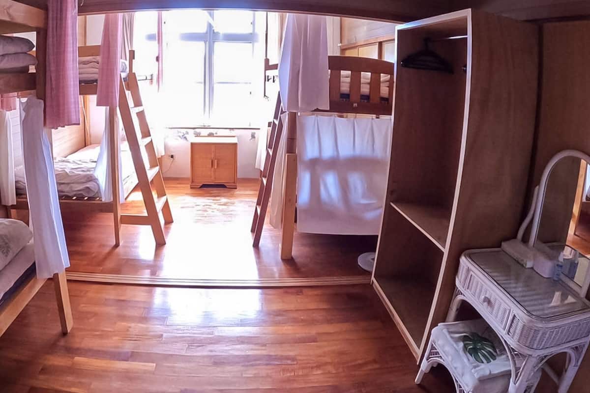 A compact room with bunk beds, a wooden desk, and a small wardrobe.