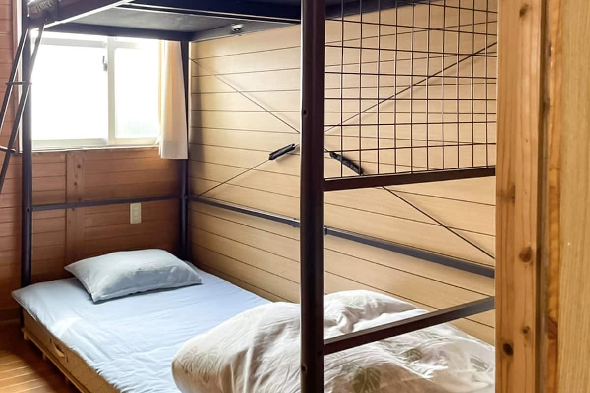 A bunk bed room with wooden walls, a window, and a ladder.