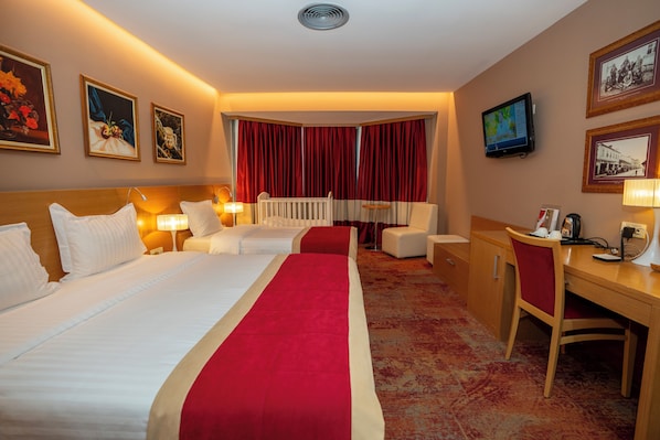 Une chambre d’hôtel avec deux lits, un bureau, une chaise, une télévision et des œuvres d’art accrochées aux murs.