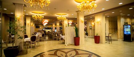 Vestíbulo de hotel con candelabros, un diseño floral en el suelo y varias zonas de estar.
