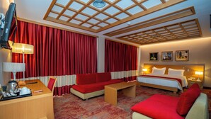 Une chambre d’hôtel avec un lit, deux canapés, un bureau et une télévision.