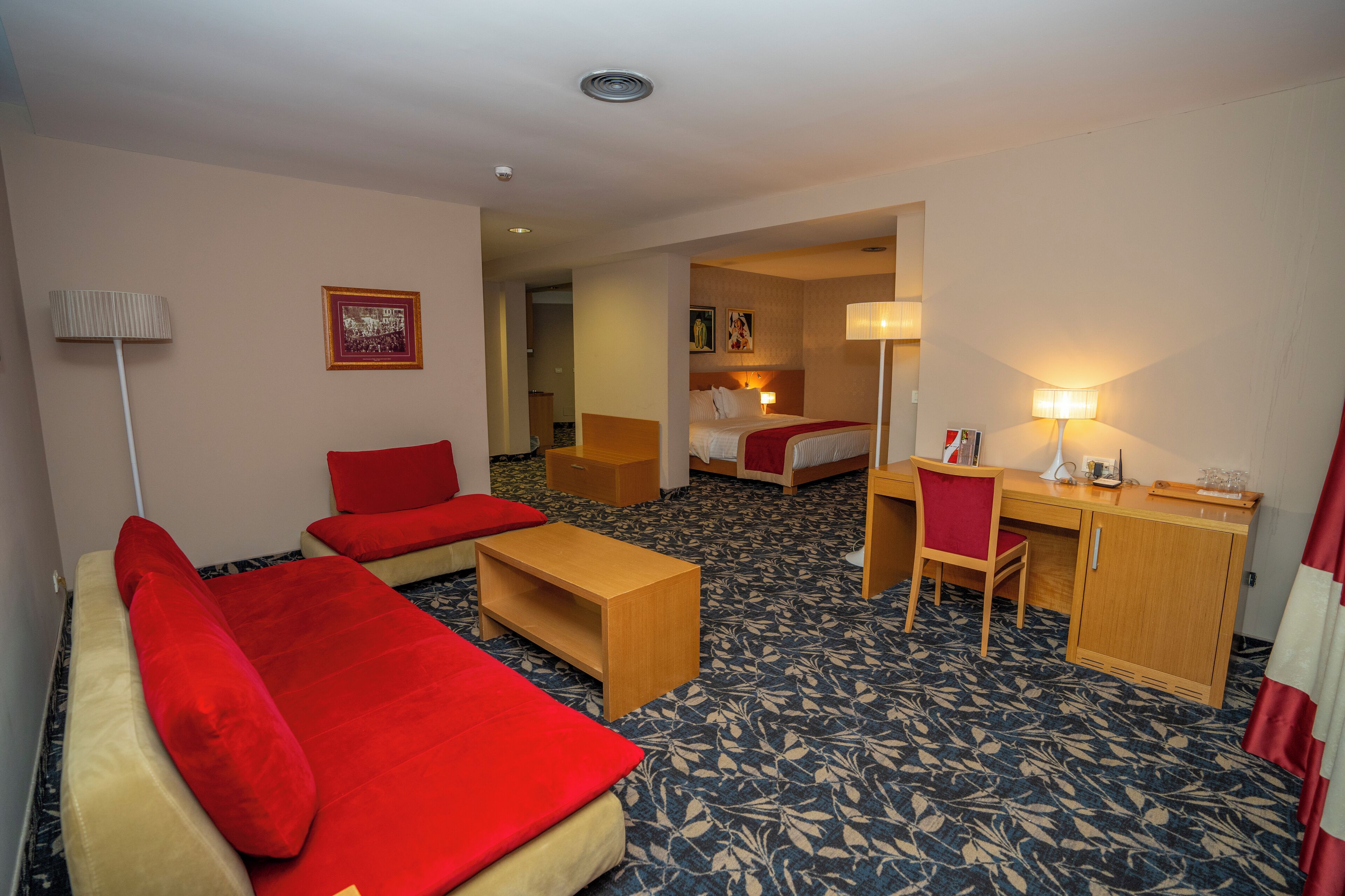 Una habitación de hotel con una cama, un escritorio, una silla, un sofá y una mesita.