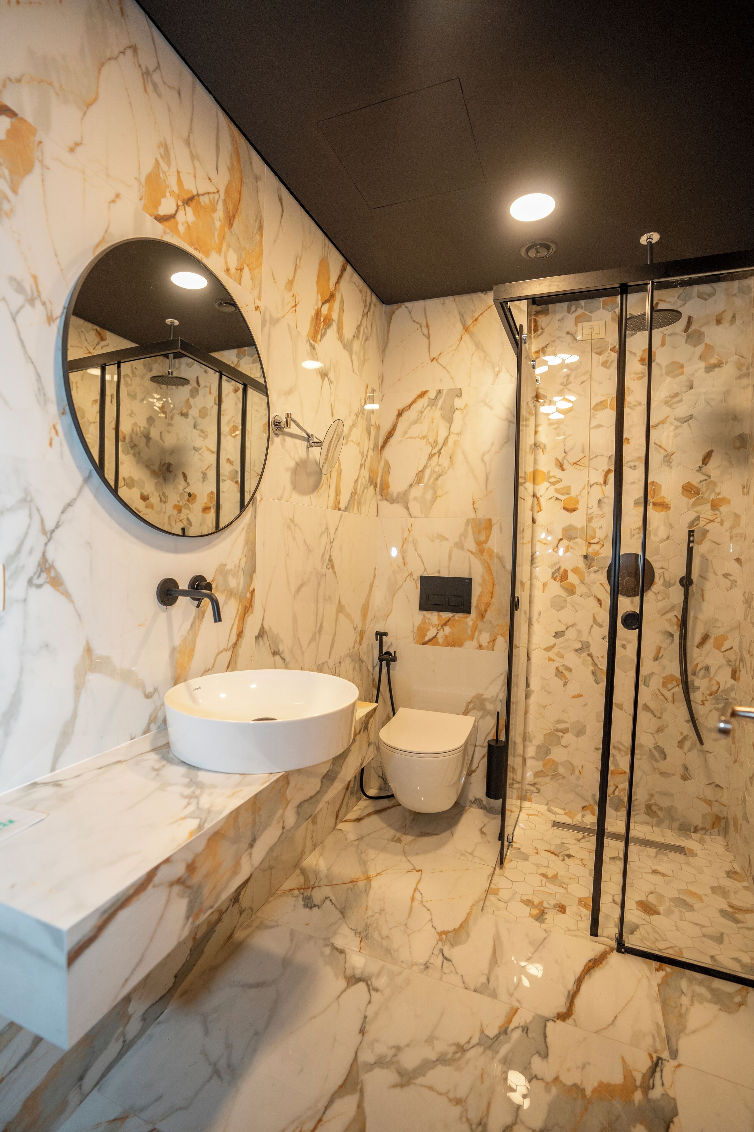 A bathroom with a marble sink, a toilet, and a glass-enclosed shower.