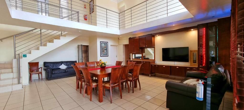 Un grand espace de vie comprenant une table à manger, des canapés, un escalier et un coin cuisine.