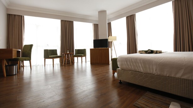 Een hotelkamer met een groot bed, een televisie, een bureau en twee stoelen.