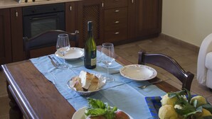 A dining area with a table set for two, featuring a plate of fruit, bread, and a bottle of wine. - Milord Relais (Massa Lubrense)