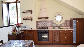 A kitchen with wooden cabinets, a stove, oven, and a window. - Milord Relais (Massa Lubrense)