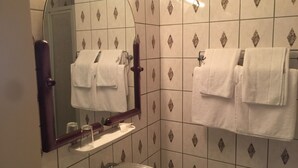A bathroom with a sink, mirror, and two towel racks with white towels. - Hotel Marjani (Sarstedt)