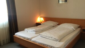 A double bed with white linens in a hotel room. - Hotel Marjani (Sarstedt)