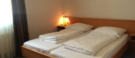 A double bed with white linens in a hotel room.