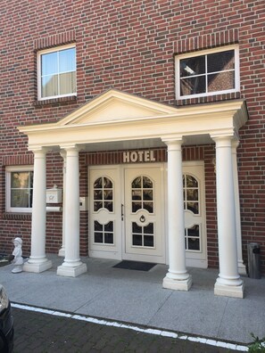 A hotel entrance with a classic facade, featuring a central entrance flanked by columns and a pediment above the doors. - Hotel Marjani (Sarstedt)