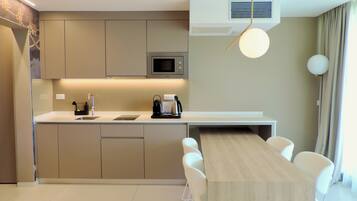 Een moderne keuken met een ingebouwde magnetron, een koffieapparaat en een eethoek met een houten tafel en witte stoelen.