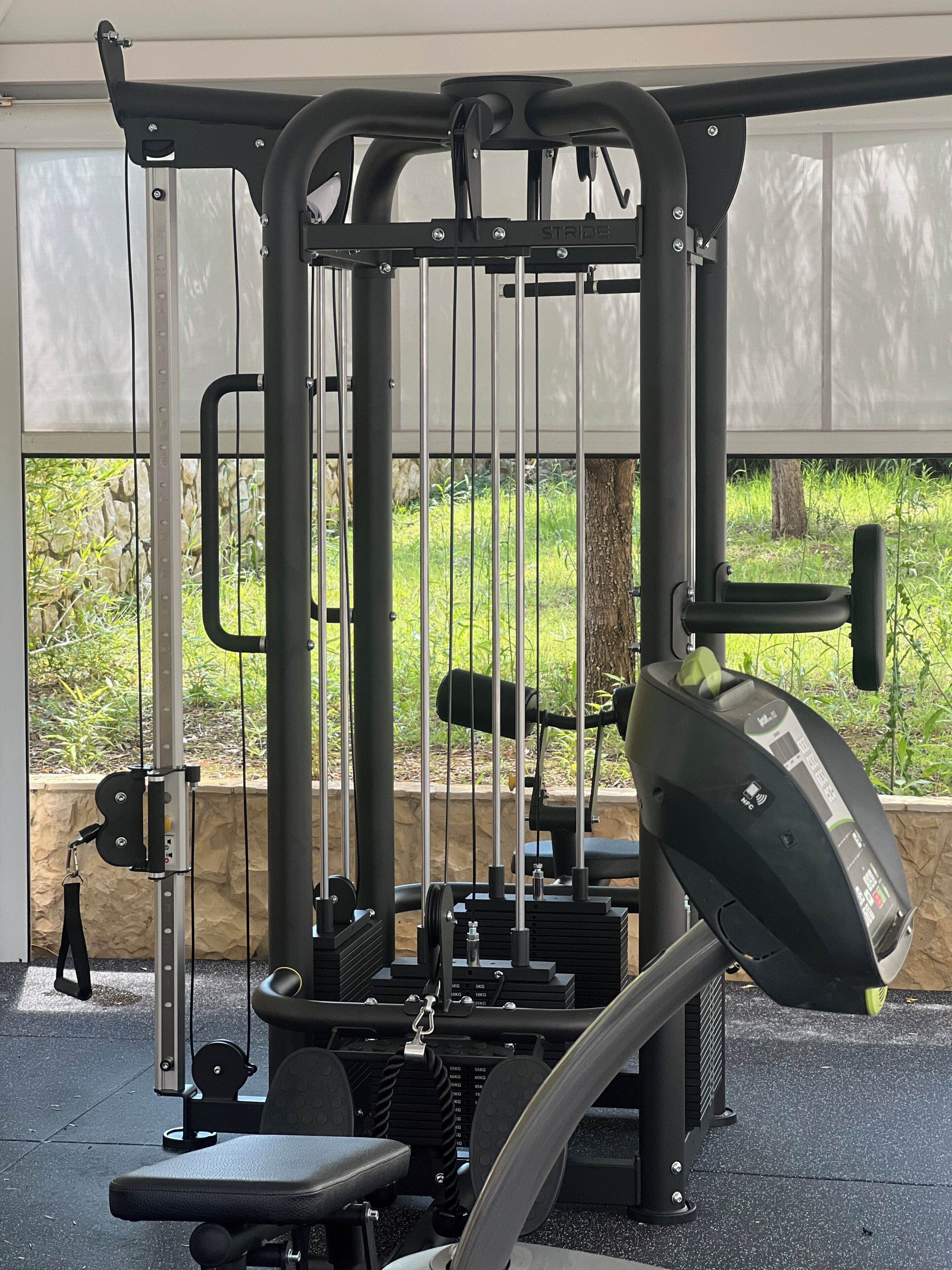 Un gimnasio con barra de dominadas, banco de pesas y apilamiento de pesas.