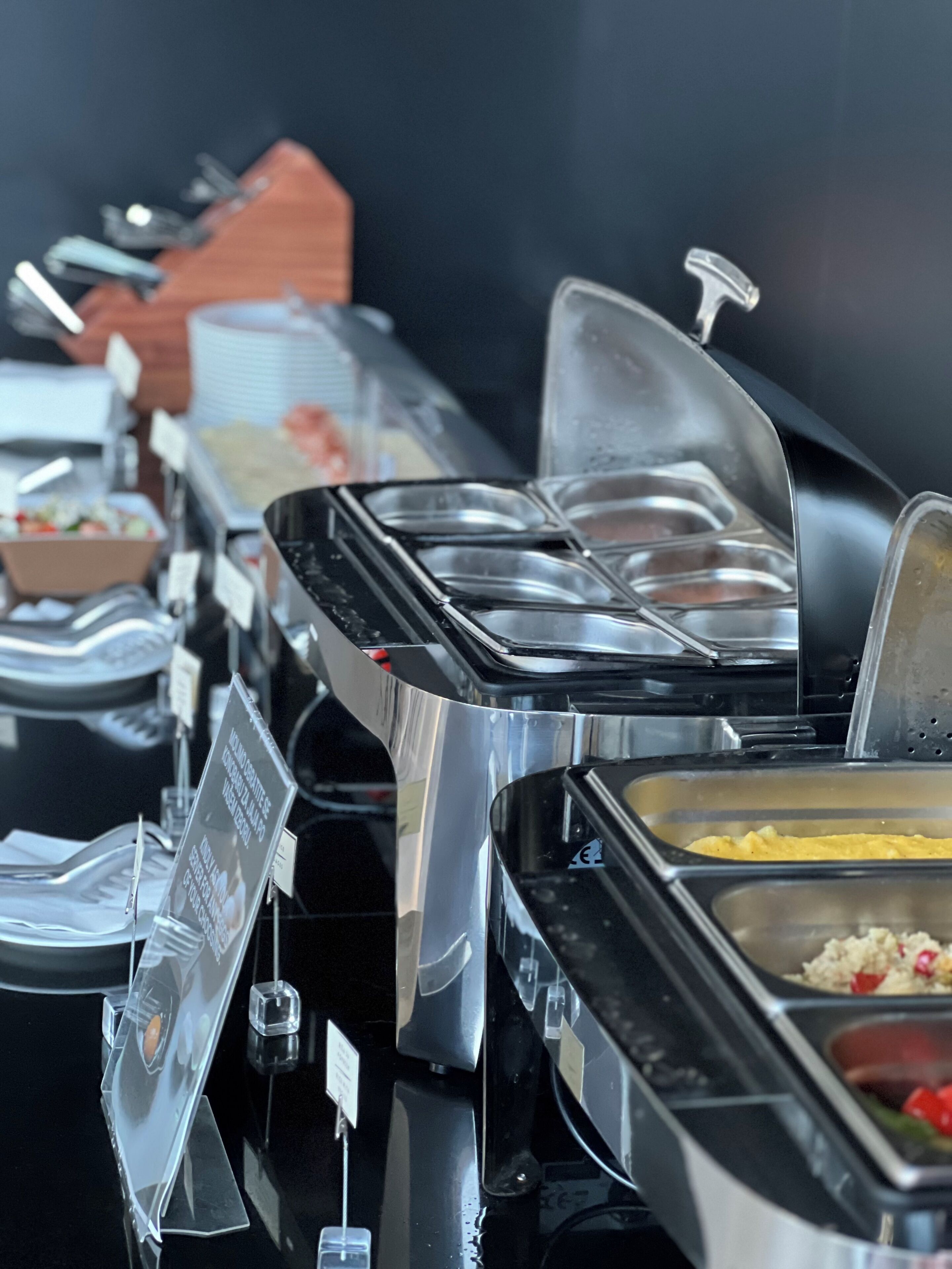 A buffet setup with various food containers and a sign.