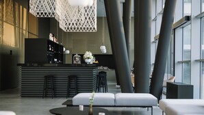 Un bar moderno con barra, taburetes y una zona de estar con sofás y una mesa de centro.