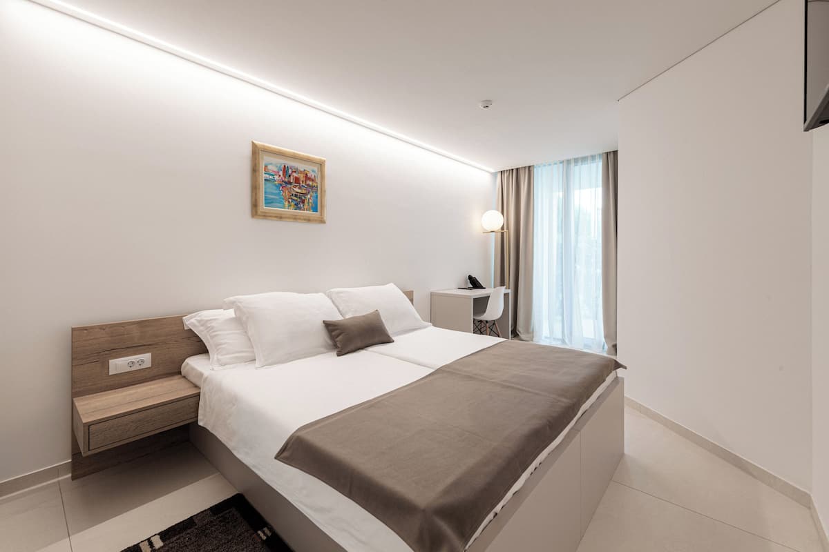 Una habitación de hotel moderna con una cama grande, una mesita de noche y un escritorio con una silla.