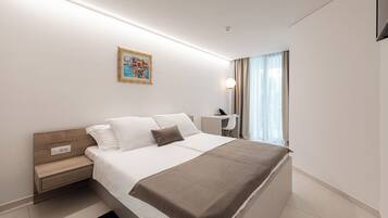 Ein modernes Hotelzimmer mit einem großen Bett, einem Nachttisch und einem Schreibtisch mit Stuhl.